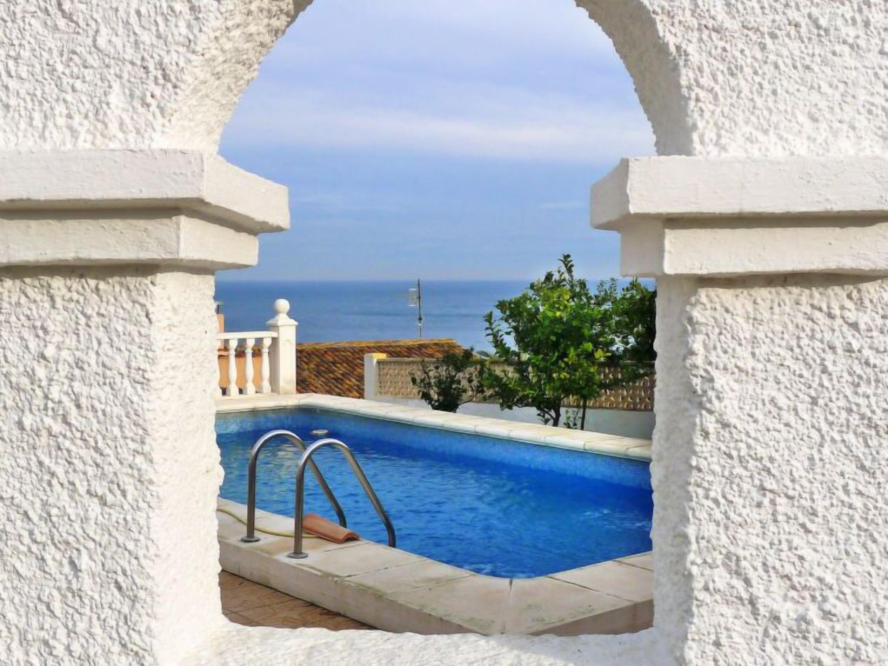 A pool with a view of the sea, framed by white pillars.