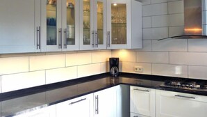 A modern kitchen with white cabinets, a black countertop, and a stainless steel range hood. - Vacation home Avalon by Interhome (Calpe/Calp)