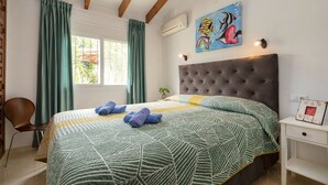A bedroom with a large bed, green curtains, a painting of fish, and a small bedside table. - Vacation home Avalon by Interhome (Calpe/Calp)