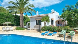 A pool area with a clear blue pool, lounge chairs, and a palm tree. - Rocinante by Interhome (Jávea)
