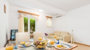 Un coin repas avec une table mise pour le petit-déjeuner, comprenant des fruits, des viennoiseries et des boissons.