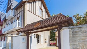 A two-story building with a covered entrance and a stone wall. - Le Cyclamen by Interhome (Courseulles)