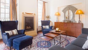 A living room with a fireplace, two armchairs, a sofa, a coffee table, and a chandelier. - Le Cyclamen by Interhome (Courseulles)