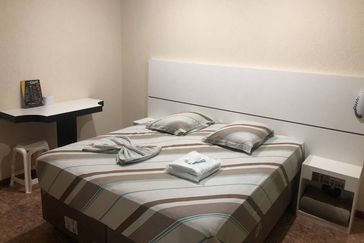 Une chambre d’hôtel avec un lit, une table de chevet, un bureau et une chaise.