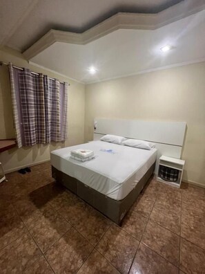 A bedroom with a bed, curtains, and a small bedside table. - Hotel City II (Santo André)