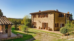 Un edificio in pietra con tetto in tegole, circondato da un giardino curato e un vialetto in pietra.