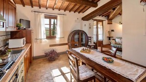 Una cucina rustica con travi in legno, un tavolo da pranzo con sedie e vista sull'esterno attraverso una finestra.