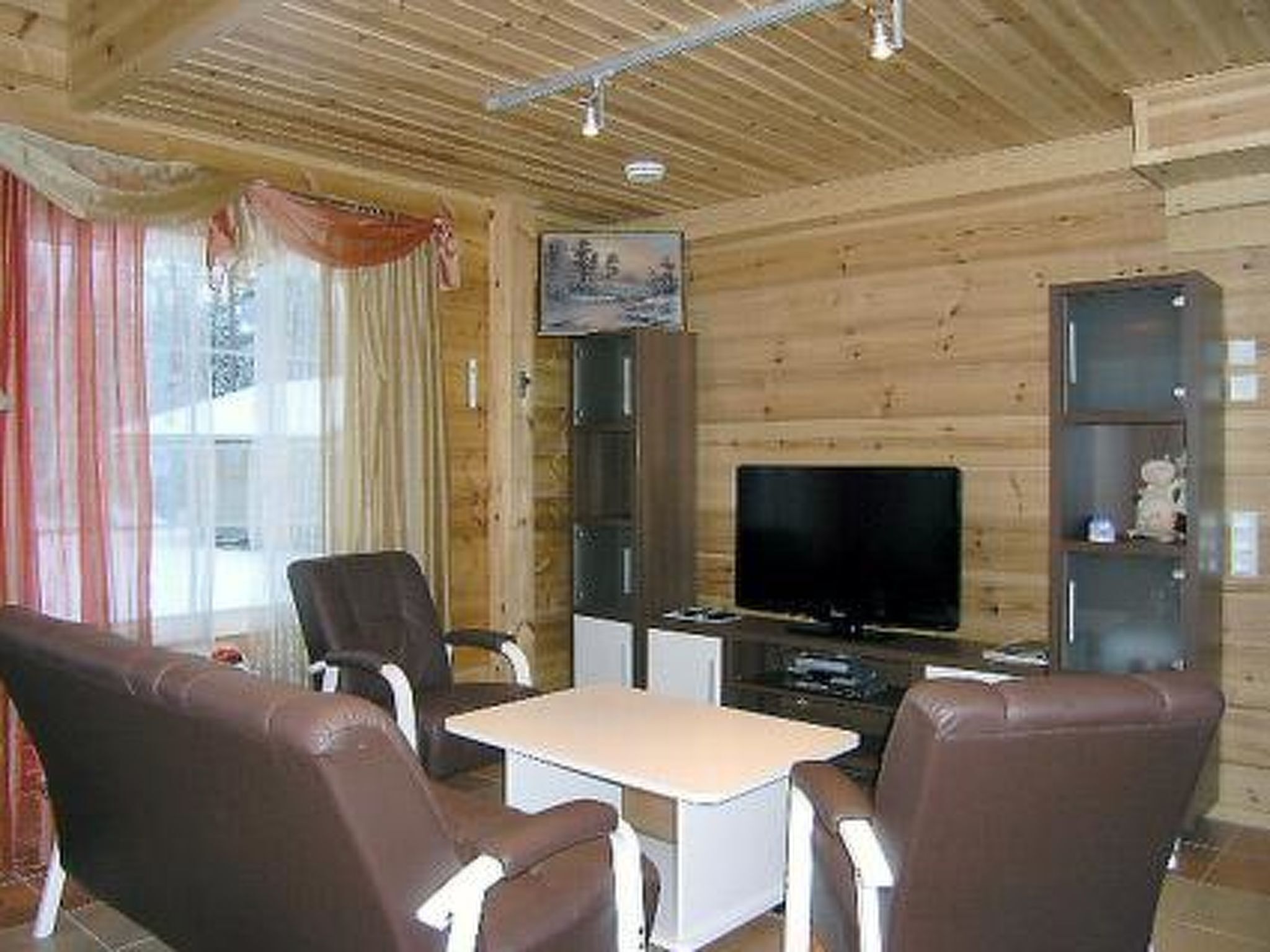 A cozy cabin interior with a wooden interior, a television, and seating arrangements.