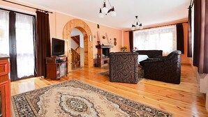 Un salón espacioso con piso de madera, un tapete grande, una chimenea y un televisor.