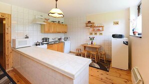 Cocina compacta con una isla central, armarios de madera y una lámpara colgante.