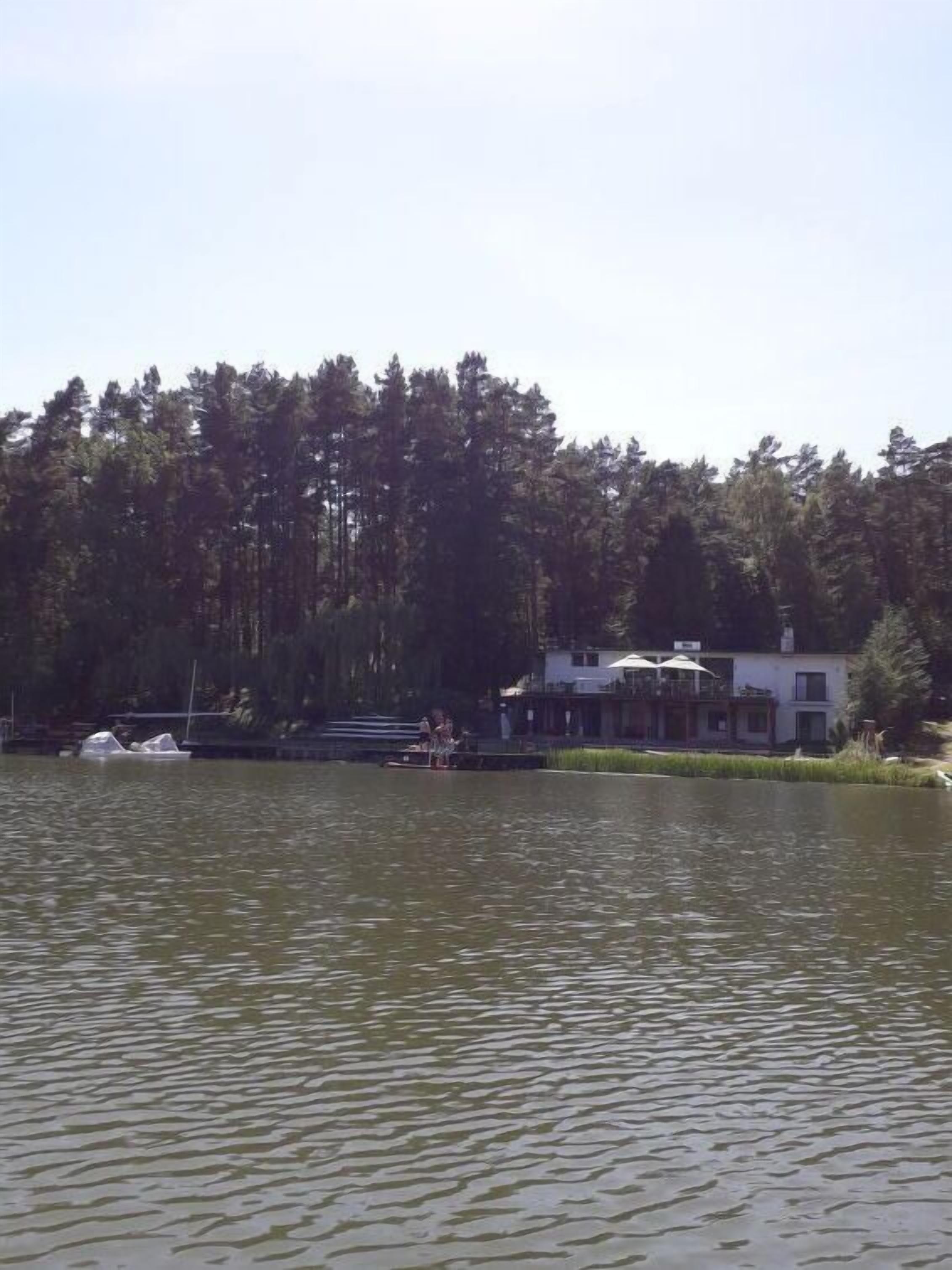 A lakeside property with a dock, a boat, and a building with a balcony.