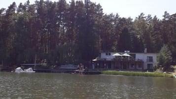 En fastighet vid en sjö med en brygga, en båt och en byggnad med en balkong.