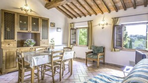 Una habitación acogedora con una mesa de madera, sillas, una cama y un ventanal con vistas a follaje.