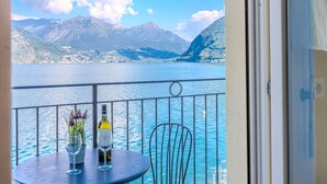 Un balcon avec une table, deux verres à vin et une bouteille de vin.