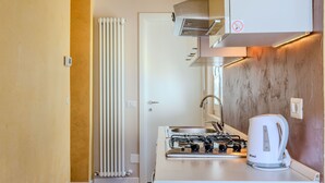 Une cuisine compacte équipée d’une cuisinière à gaz, d’une bouilloire et d’un four encastré.