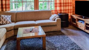 A cozy living room with a sofa, a coffee table, and a TV.