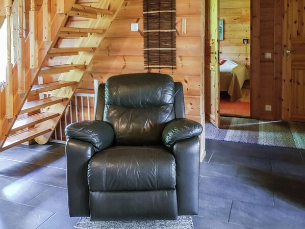 A black leather chair in a room with a wooden staircase and a door leading to another room. - Lomamaja rukaranta 6 b by Interhome (Kuusamo)