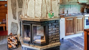 A stone fireplace with a modern kitchen in the background.
