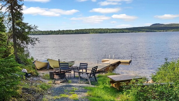 A lakeside setting with a dock, a table, and chairs for outdoor dining.