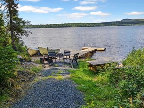 Un entorno junto al lago con un muelle, una mesa y sillas para comer al aire libre.