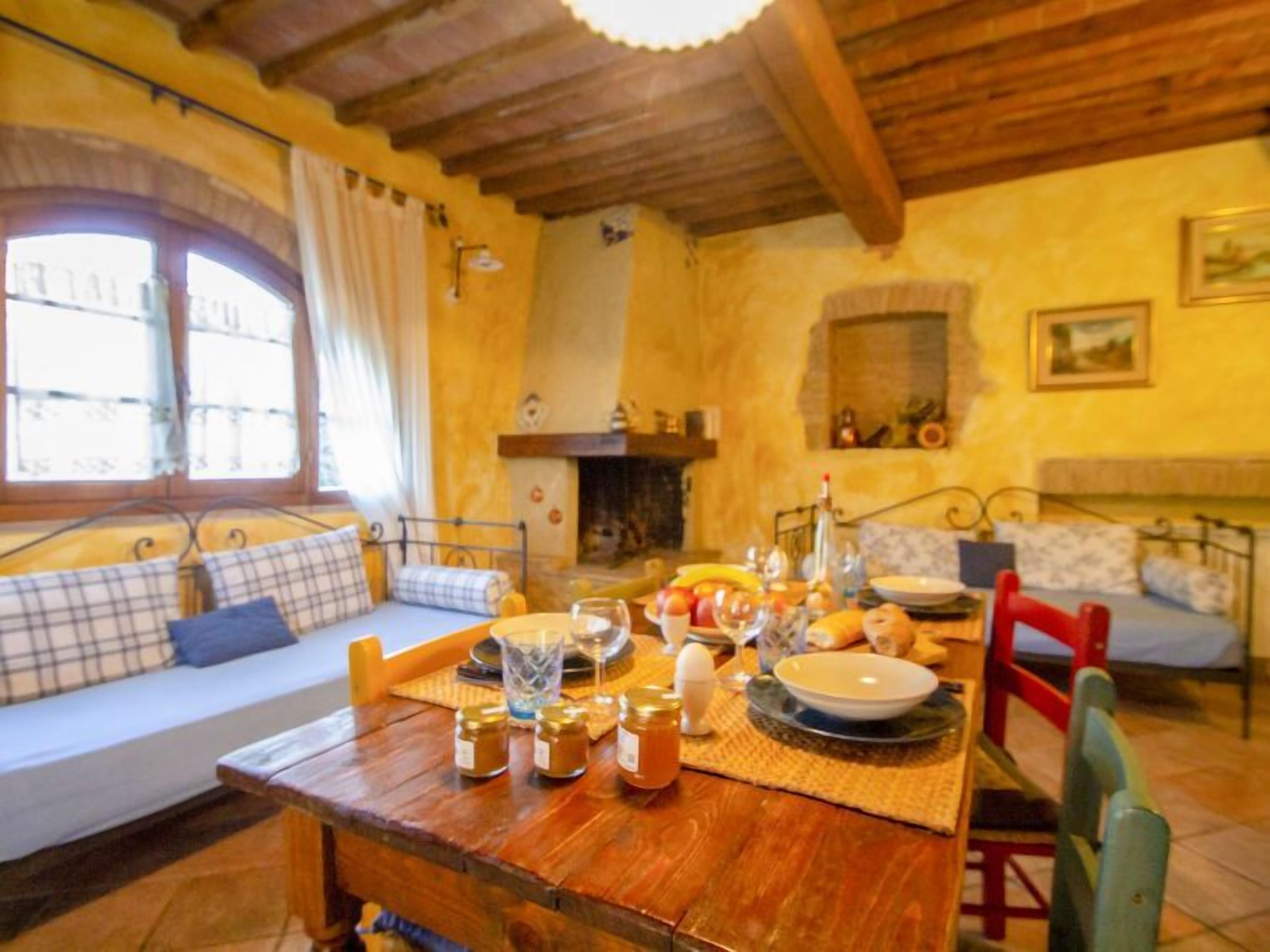 Una stanza accogliente con un tavolo di legno apparecchiato per la colazione, un divano con cuscini e un camino.