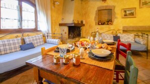 Ein gemütliches Zimmer mit Holztisch, gedecktem Frühstück, einer Couch mit Kissen und einem Kamin.