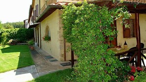 Ein traditionelles Steinhaus mit überdachter Terrasse und üppigem Garten.