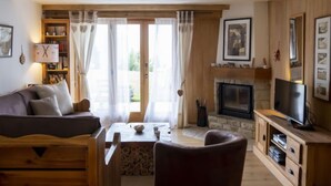 A cozy living room with a sofa, a fireplace, a television, and a bookshelf.