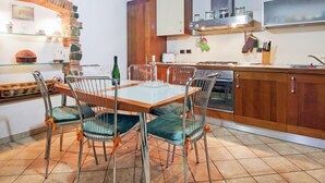 A kitchen with a wooden ceiling, a dining table with chairs, and a tiled floor.