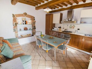 Un coin repas accueillant avec une table et des chaises, une cuisine dotée de meubles en bois et un arc en pierre.
