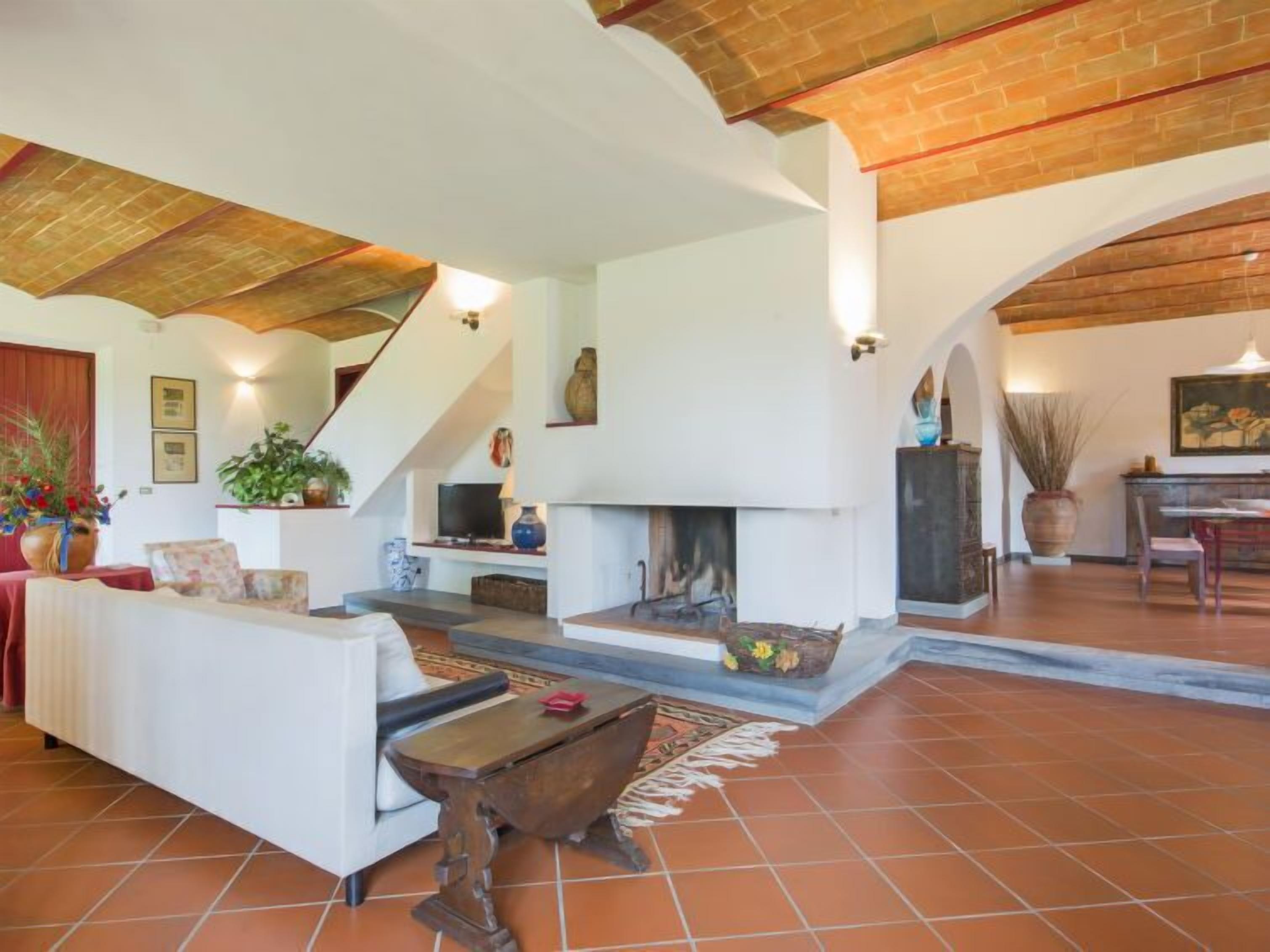 A spacious living area with a fireplace, white sofas, a wooden coffee table, and a staircase leading to an upper level.