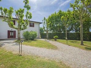 Un bâtiment blanc avec des volets rouges et une allée de gravier menant à un chemin pavé.