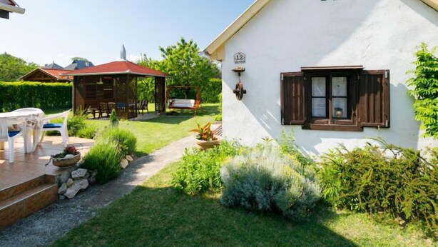 Ein weißes Haus mit einer kleinen Veranda und einer Schaukel im Garten.
