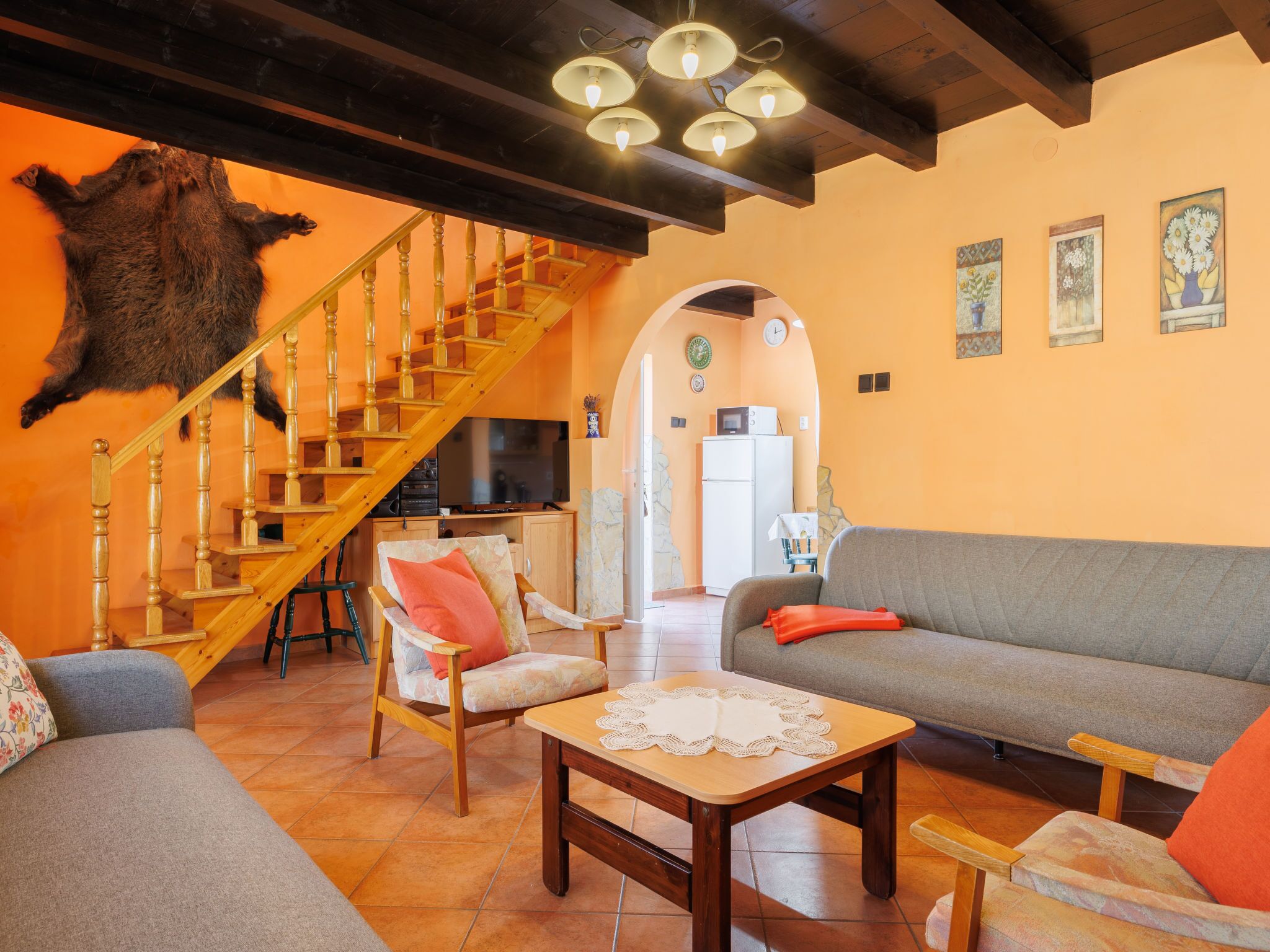 Un salon avec un escalier en bois, un canapé, un fauteuil et une table.