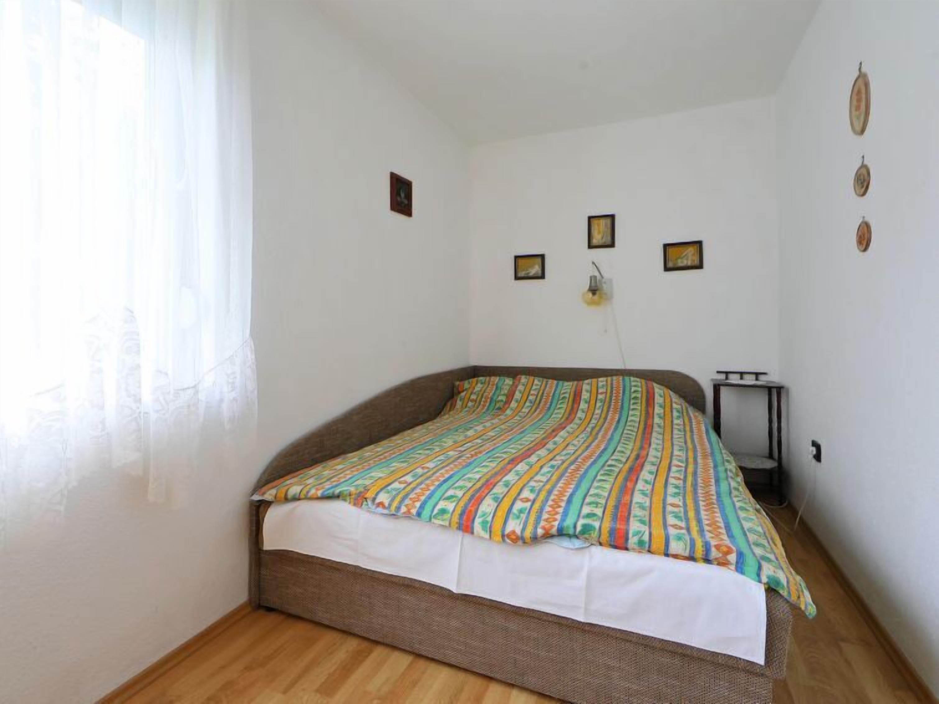 A single bed with a colorful striped bedspread, a bedside table, and a wall-mounted lamp.