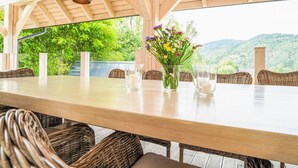 An outdoor dining area with a wooden table, wicker chairs, and a vase of flowers. - Willa Sonia by Interhome (Zawoja)