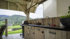 A wooden deck with a built-in kitchen area, including a sink, a grill, and a large bowl. - Willa Sonia by Interhome (Zawoja)