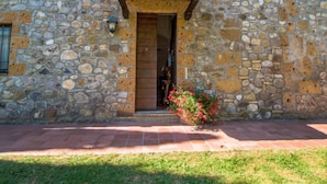 Un edificio de piedra con puerta de madera y un pequeño jardín lleno de flores.