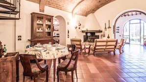 Un comedor amplio con techo de ladrillo, un mueble de madera con puertas de vidrio y una chimenea.
