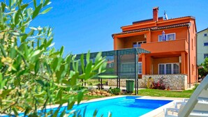 A swimming pool with lounge chairs, a glass enclosure, and a building with a stone facade in the background. - Vacation home Marko by Interhome (Novigrad (Istra))
