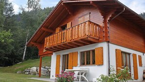 A wooden chalet with a balcony, white exterior walls, and wooden shutters. - Elorian by Interhome (Ovronnaz)
