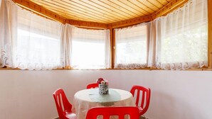 Una habitació amb sostre de fusta, una taula rodona amb mantell de puntes i quatre cadires vermelles.