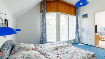 A bedroom with a bed, a fan, and a window with curtains.