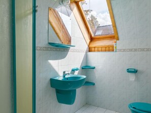 A bathroom with a skylight, a sink, and a toilet.