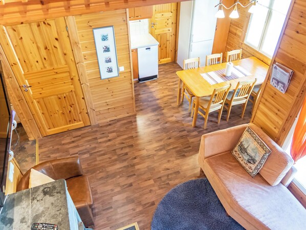 Un interior de madera con comedor, un sofá y una pequeña cocina.