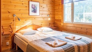 Una habitación acogedora de madera con una cama, dos lámparas de noche, una ventana con persianas y una obra de arte enmarcada en la pared.