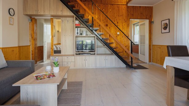 Een moderne woonkamer met een trap, houten wanden en een keukenhoek.