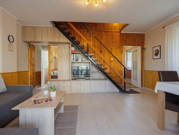 Un salon moderne avec un escalier, des murs en bois et un coin cuisine.