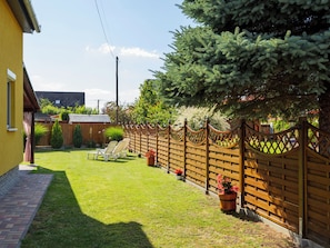 Un jardin bien entretenu, avec une clôture en bois, une pelouse et un petit espace aménagé pour s’asseoir.