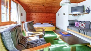 Una cabaña acogedora con techo de madera, una cama, un sofá, un televisor y una mesa de comedor.
